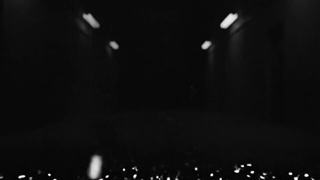 Surreal transition through a dark, empty tunnel illuminated by overhead lights and mysterious vapor.