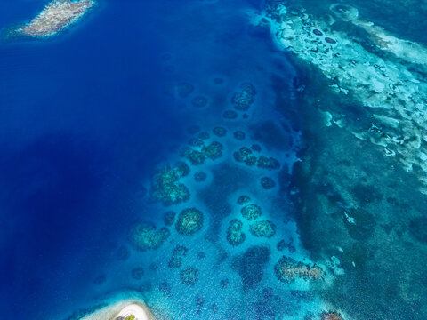 Aerial view of the vibrant coral reefs and turquoise waters surrounding the island of Guanaja, Bay Islands Department, Honduras.