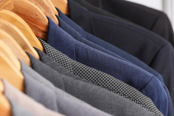Obraz premium Rack with different stylish male suits in dressing room, closeup