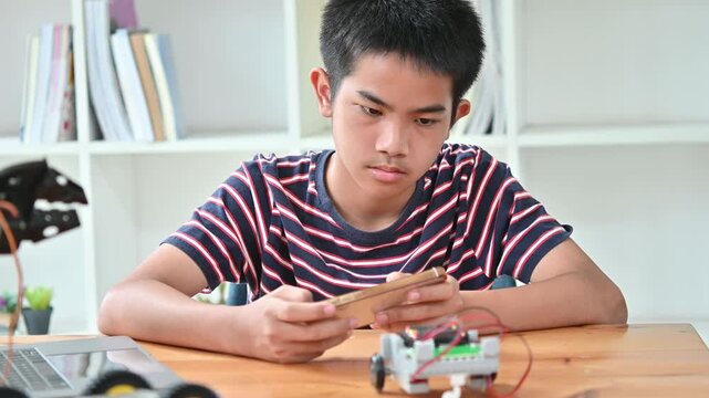 Smart Little Boy Use Smartphone To Control Robotic Toy In Education Class