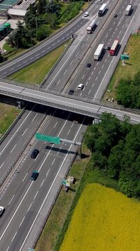 Highway Interchange in Motion: An aerial view showcases a bustling highway interchange with cars and trucks navigating multiple lanes under a clear sky.