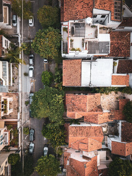 Aerial view of the Urca neighborhood featuring traditional red clay rooftops, lush green trees, and parked cars along a narrow street in Rio de Janeiro, State of Rio de Janeiro, Brazil.