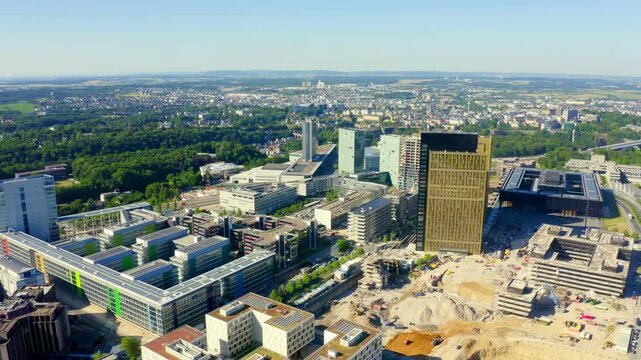 Luxembourg City, Luxembourg. The Court of Justice of the European Union towers, golden anodized aluminum facades catching sunlight, Drone footage over the Kirchberg Plateau. Drone footage, Point of i
