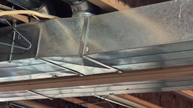 Residential basement HVAC ductwork and exposed utility infrastructure in unfinished interior home maintenance setting