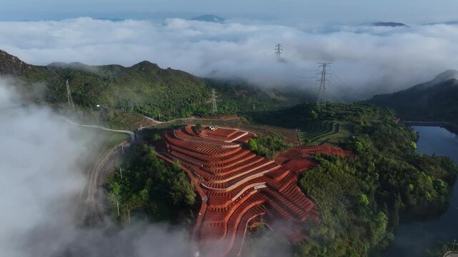 Aerial view of mountain tea plantations with terraced fields surrounded by sea of clouds and red soil
