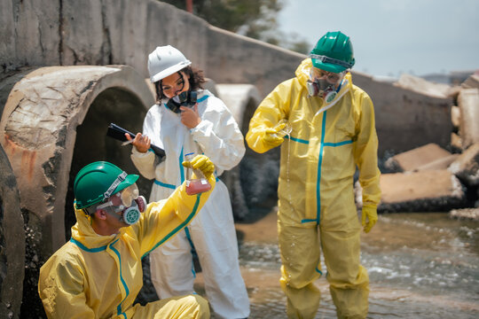 Scientists collecting polluted liquid samples from contaminated drainage canal to evaluate industrial wastewater toxicity and environmental damage in coastal ecosystem area.