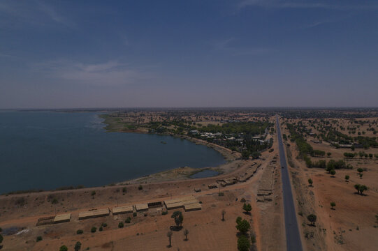 Aerial view of the Minjibir reservoir and surrounding arid landscape with a straight road and scattered vegetation in Kano, Kano State, Nigeria.