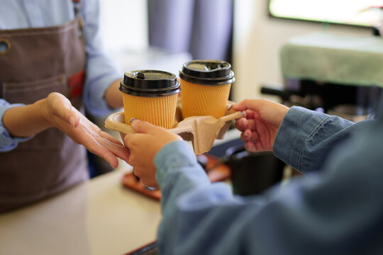 barista serving takeaway coffee drinks to customer hands holding paper cup tray cafe counter small business service hospitality food beverage industry worker