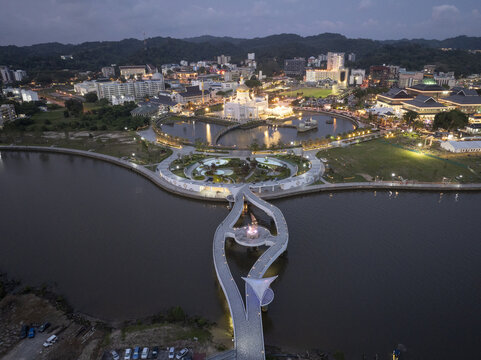 Aerial view of the illuminated Omar Ali Saifuddien Mosque and the modern pedestrian bridge at Taman Mahkota Jubli Emas during twilight Bandar Seri Begawan, Brunei-Muara District, Brunei.