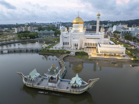 Aerial view of the Sultan Omar Ali Saifuddien Mosque with its golden dome and ceremonial stone boat in the lagoon at dusk in Bandar Seri Begawan, Brunei-Muara District, Brunei.