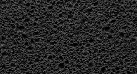 Fototapeta premium Textured black porous volcanic rock surface with rough pits and deep shadows Wallpaper Background image