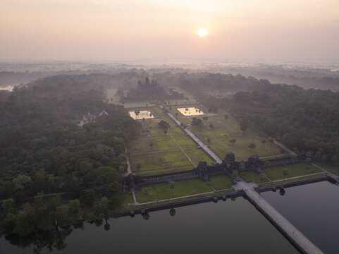 Aerial view of Angkor Wat temple complex at sunrise with misty surroundings and lush vegetation Krong Siem Reap, Siem Reap Province, Cambodia.