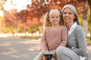 Fototapeta premium Cute little girl with photo camera and her mother in park on autumn day