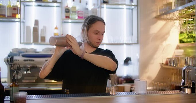 Bartender shaking. Mixology bar. Man making cocktail with professional tool in cafeteria bar interior. Mixing beverage ingredient process.