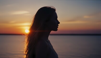Fototapeta premium 海辺の美しい夕日を見つめる女性の横顔のシルエット、シネマティック