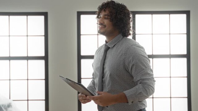 Man wearing shirt and tie holding clipboard gestures thumbs up inside empty house building; home selling trust confidence.