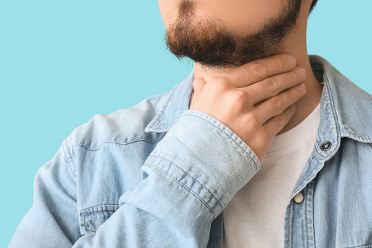 Young man with thyroid gland problem on blue background, closeup