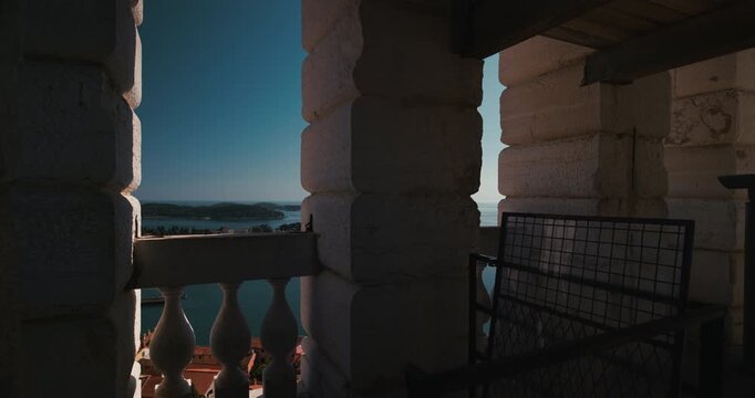 Camera pan inside a church tower balcony overlooking the coastline and sea near Rovinj.