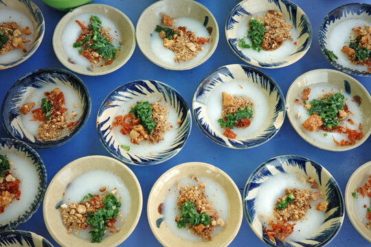 high-quality photo of vietnamese steamed rice cakes known as banh beo served in traditional small ceramic bowls with scalloped edges topped with minced shrimp scallion oil and crispy pork rind