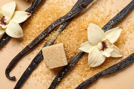 Aromatic vanilla sugar, flowers and sticks on beige background