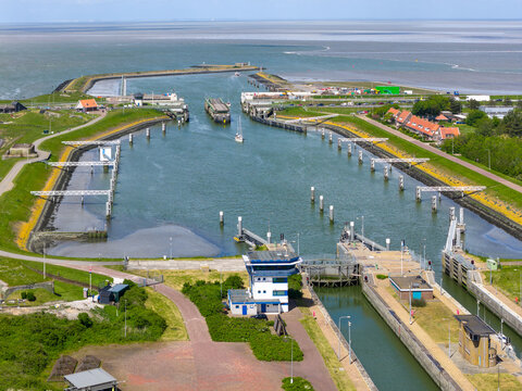 Aerial view of the Lorentzsluizen lock complex featuring water gates, control buildings, and maritime infrastructure under a clear sky in Kornwerderzand, Friesland, Netherlands.