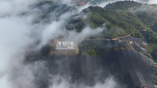 Aerial view of solar power station with photovoltaic panels in misty mountains