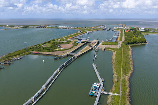 Aerial view of Lorentzsluizen lock complex showing the water gates, green embankments, and the expansive Wadden Sea under a cloudy sky Kornwerderzand, Friesland, Netherlands.