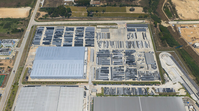 Aerial view of the BYD Thailand Rayong Office Building and expansive parking lots filled with new vehicles at an industrial facility in Phananikhom, Rayong, Thailand.