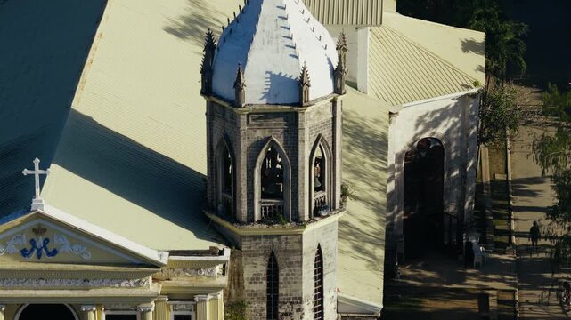 Close telephoto orbit of Dauis Church bell tower in sunny Bohol Philippines, drone