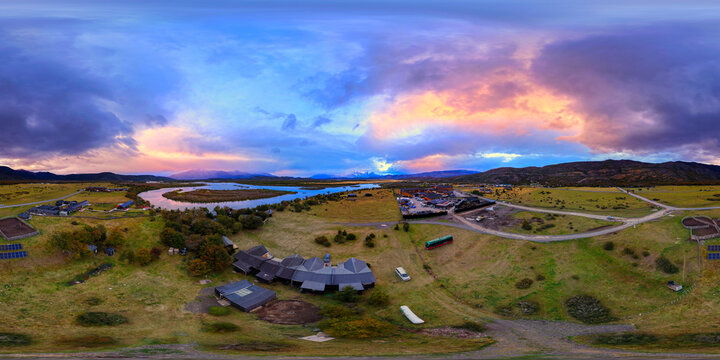Aerial view of Rio Serrano Hotel Spa near the winding Serrano River under a dramatic sunset sky in Torres del Paine, Magallanes, Chile.