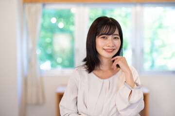 Obraz premium Asian woman smiling and looking at camera in bright indoor setting