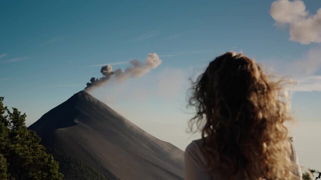 Woman watching ash plume rising from Fuego volcano eruption in Guatemala