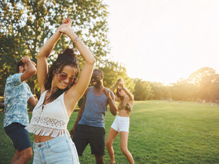 Obraz premium Festivalgoers Dancing in a Sunlit Park with Joyful Summer Energy