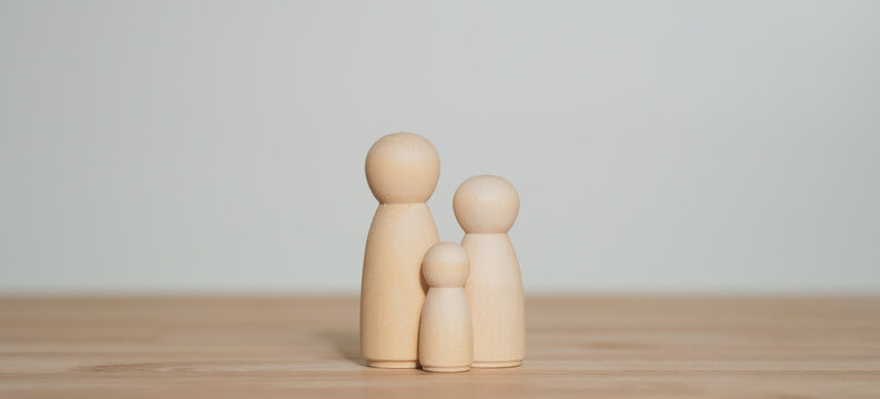 Conceptual wooden dolls forming a small family illustrating parenting responsibility, social expectations and hope parents have for their children success.
