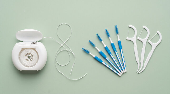 Dental Hygiene Tools with Floss, Picks, and Interdental Brushes on Green Background