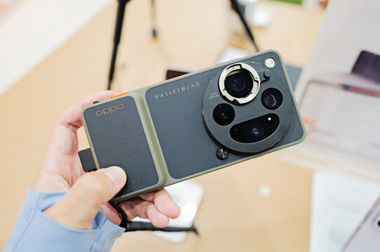 A close-up view of a person holding the OPPO Find X9 Ultra smartphone equipped with a specialized photography camera case and lens adapter on display.