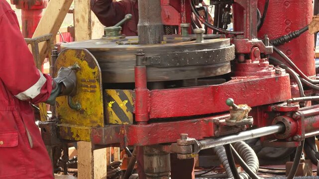 Using power tong, torque machinery, to make connection of the drill pipe in the oil drilling operation. Heavy industrial working scene footage. close-up.