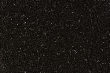 Fototapeta premium Full frame vertical background texture of coarse black Hawaiian sea salt crystals with volcanic activated charcoal showing small shiny mineral highlights