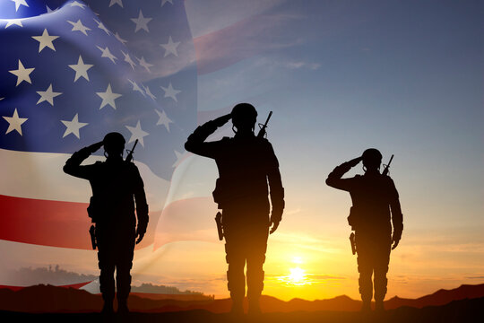 Silhouettes of a soldiers with USA flag against the sunset. Memorial Day, Veterans Day