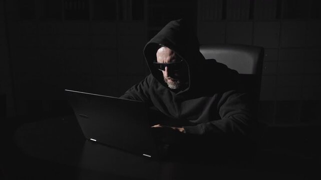 Computer hacker stealing data from a laptop. Cyber security and data protection. Hooded hacker targets blockchain. Dark Web and Cyber Security. Online hackers attack.