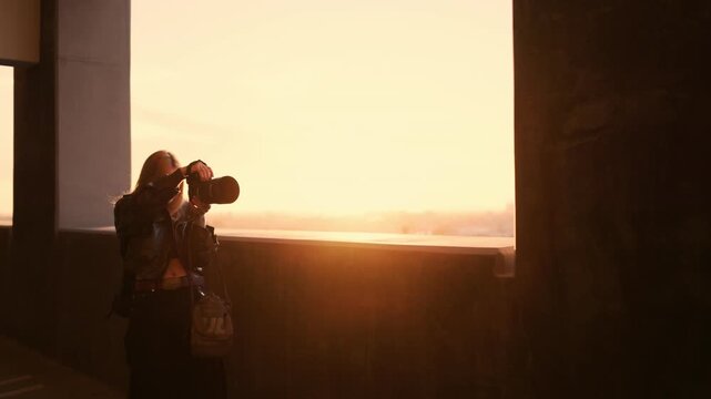 Photographer captures a fashion model with angel wings during a cinematic golden hour rooftop photoshoot with warm sunlight and dreamy atmosphere.