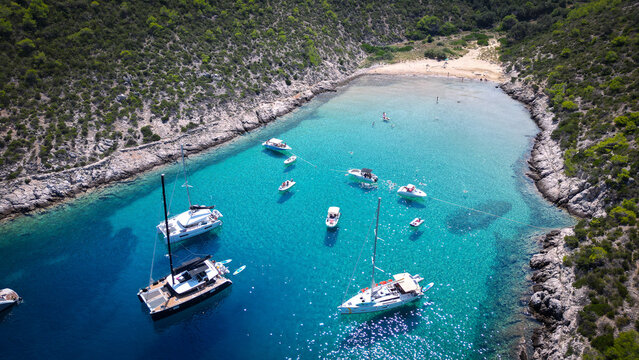 Aerial view of Smokova beach with boats anchored in turquoise waters surrounded by green hills in Vis, Splitsko-dalmatinska, Croatia.