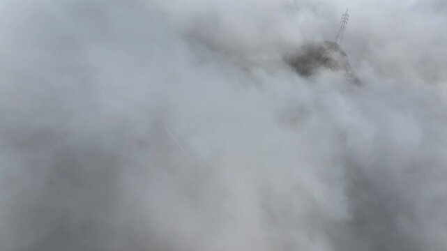 Close-up view of high voltage transmission tower partially obscured by dense fog