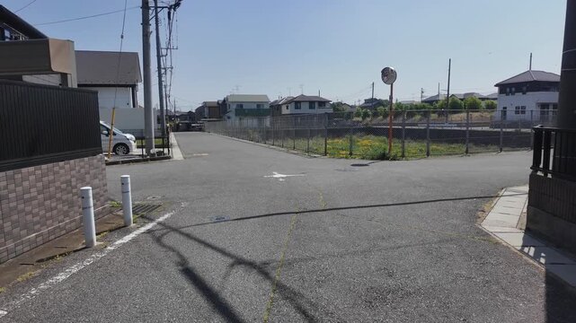 POV walking down a quiet residential street towards a fenced empty lot in Japan (Japanese text on the red pole translates to "Caution" and "Noda City")