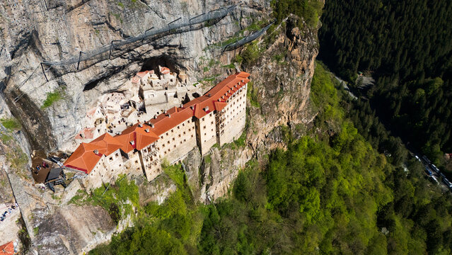 Breathtaking top-down drone perspective of the historic Greek Orthodox Sumela Monastery nestled among dense green pine woods in Trabzon, Turkey