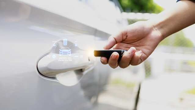 Hand holding key fob near car door handle with digital icons, modern keyless entry and smart vehicle security concept.
