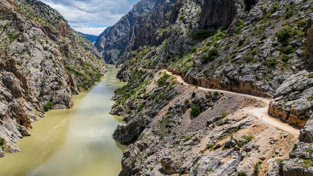 Aerial perspective flying through the deep Dark Canyon in Kemaliye, Turkey. Drone shot following the path of the Karasu River with the legendary hand-carved Stone Road visible on the cliff