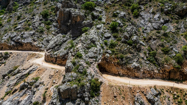 Aerial perspective flying through the deep Dark Canyon in Kemaliye, Turkey. Drone shot following the path of the Karasu River with the legendary hand-carved Stone Road visible on the cliff