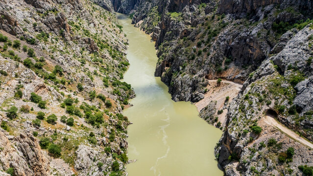 drone flight past the massive rocky cliffs of Karanlik Kanyon, Turkey. Aerial view looking down at the narrow Stone Road running along the edge of the winding river gorge