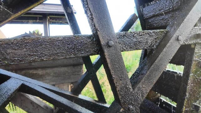 Extreme close up in slow motion of a traditional wooden water wheel showing detailed structure and dripping water at Kasumigaura Sogo Park